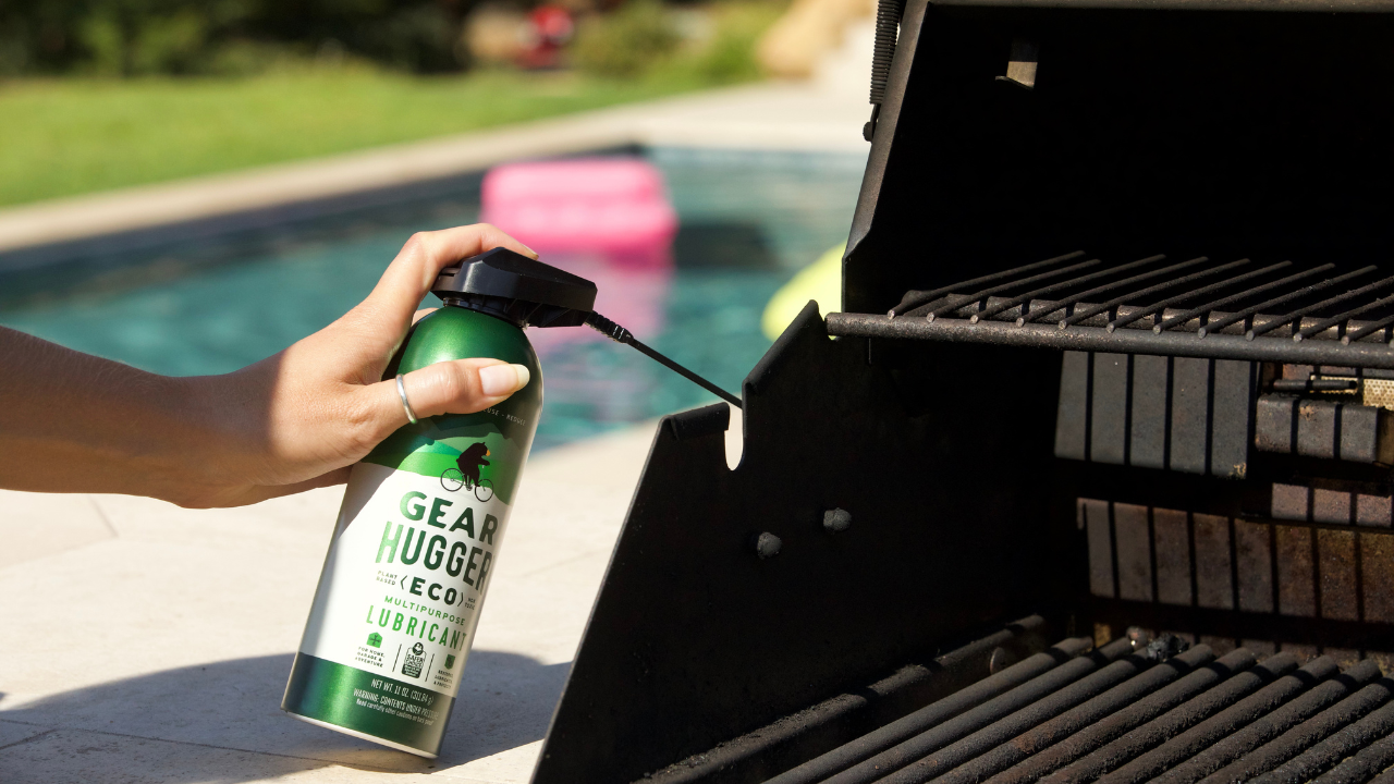 Spraying Gear Hugger eco-friendly lubricant on an outdoor BBQ to reduce toxins outside