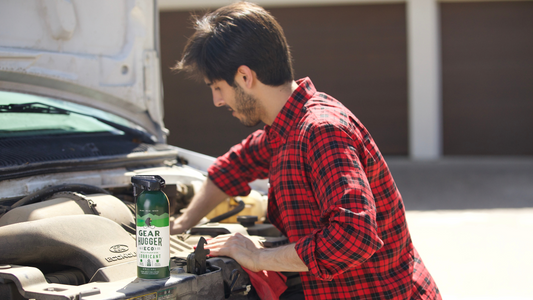 a man using spray lubricant grease on his car engine