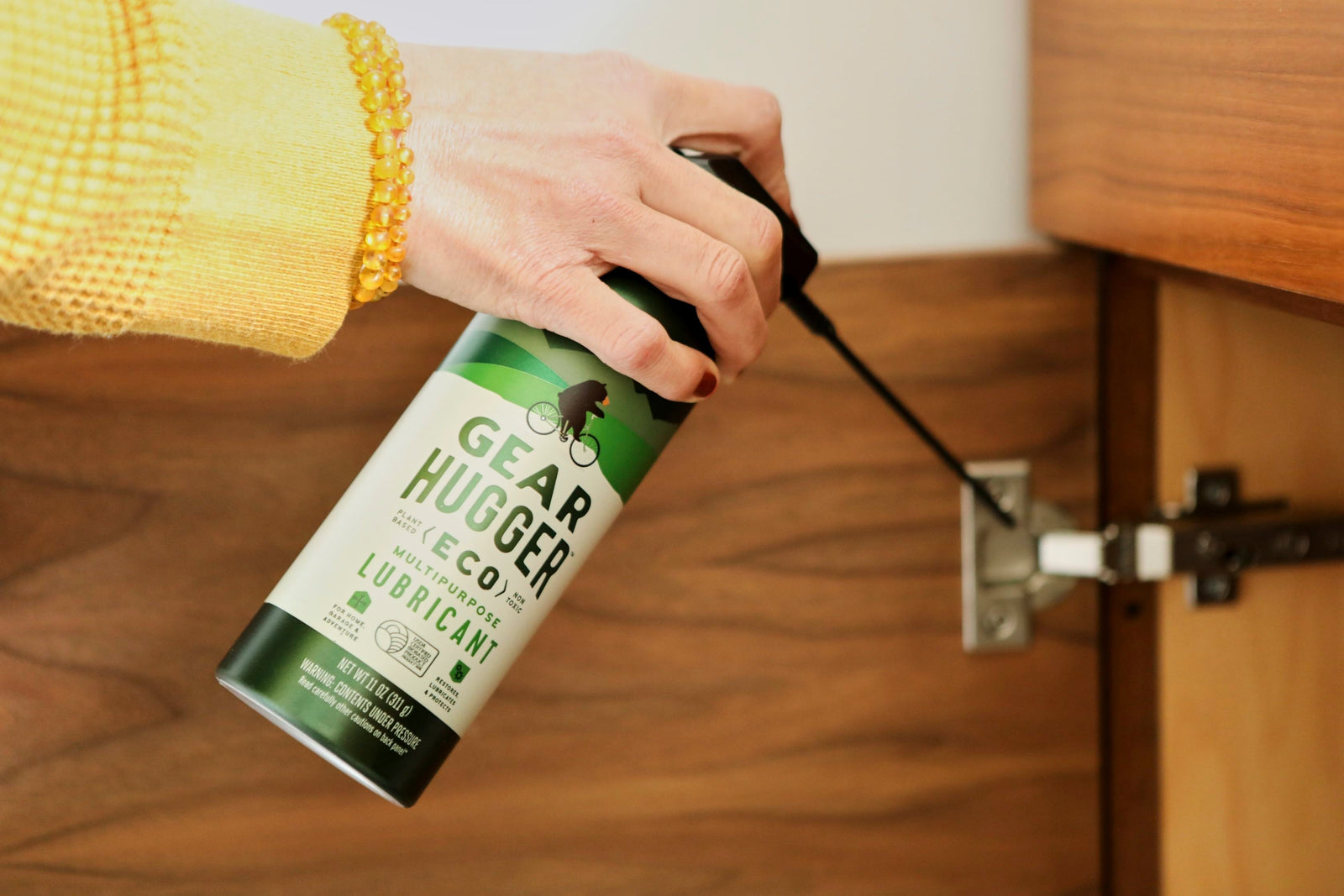 Applying Gear Hugger eco-friendly lubricant to a squeaky door hinge for smooth operation
