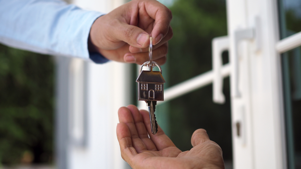 New homeowner receiving house keys at front door ready to maintain home with eco-friendly products