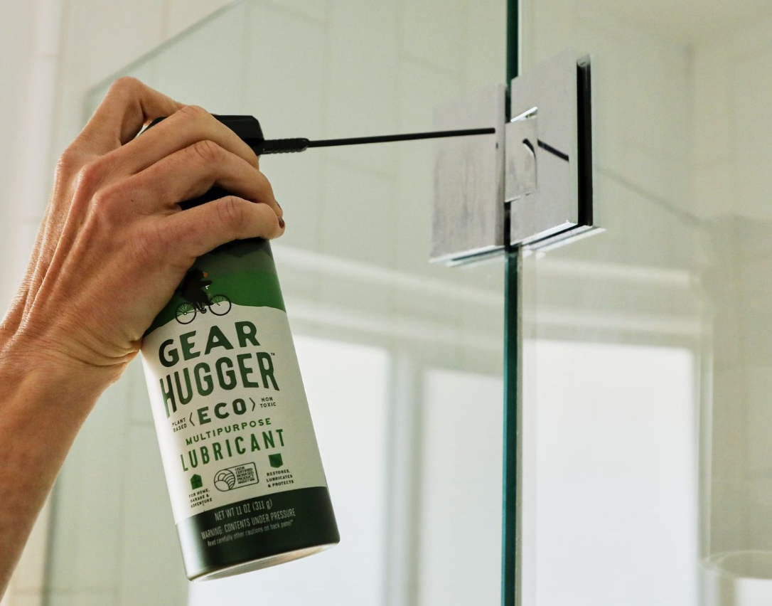 Applying Gear Hugger eco-friendly multipurpose lubricant to squeaky shower door hinges