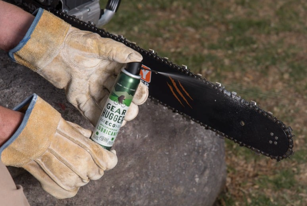 Person applying eco-friendly plant-based lubricant to a chainsaw for maintenance