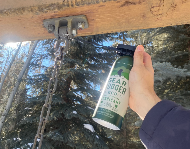 Hand applying eco-friendly plant-based lubricant to hanging porch swing chain hinges