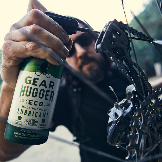 man spraying lubricant on bike spoke